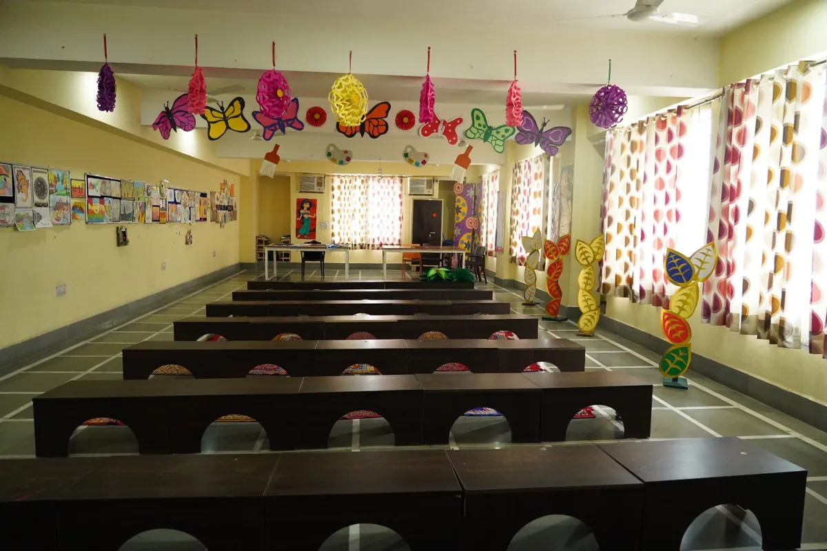 Art room with long benches, student artwork on the walls and hanging paper butterflies