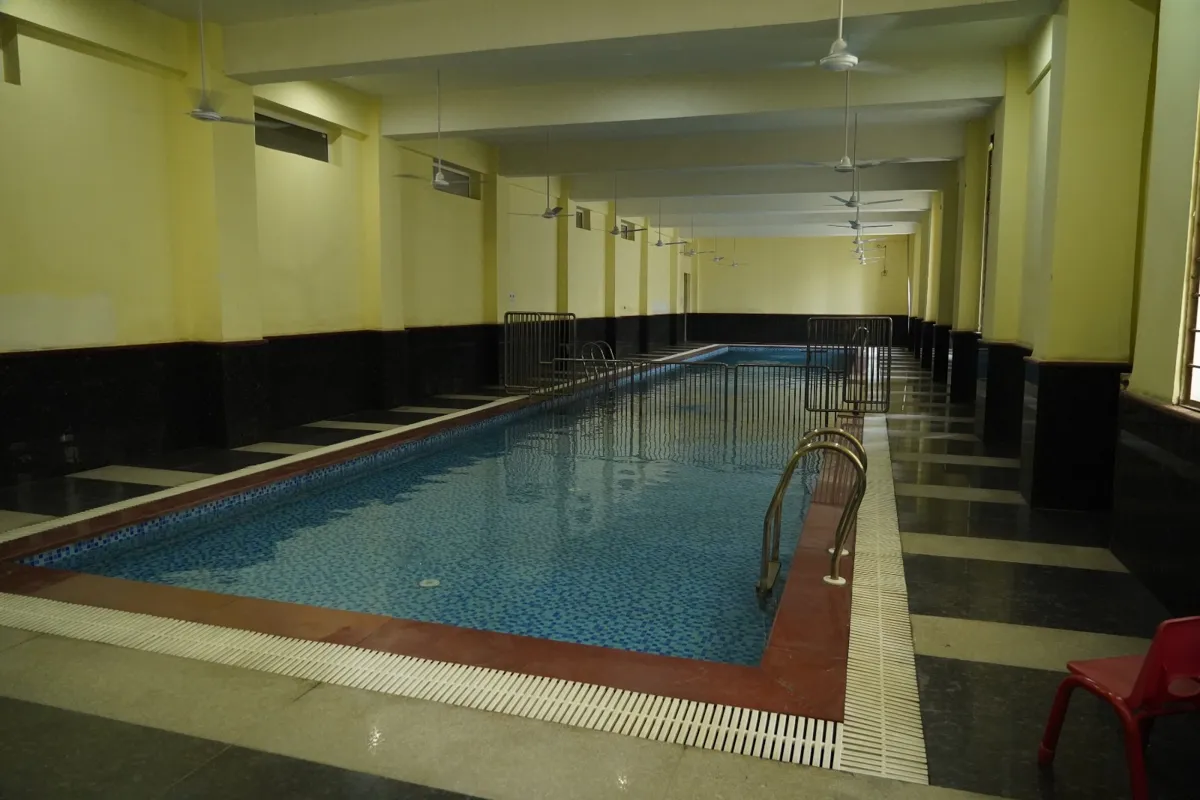 Indoor swimming pool with steel ladders and a tiled deck at SKS World School