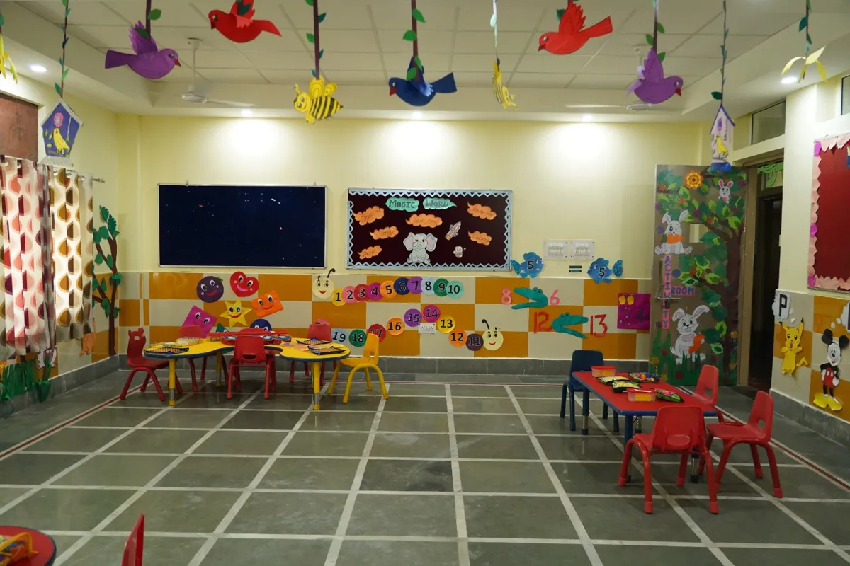 Colourful pre-primary activity room with small tables and chairs, wall murals and hanging paper birds