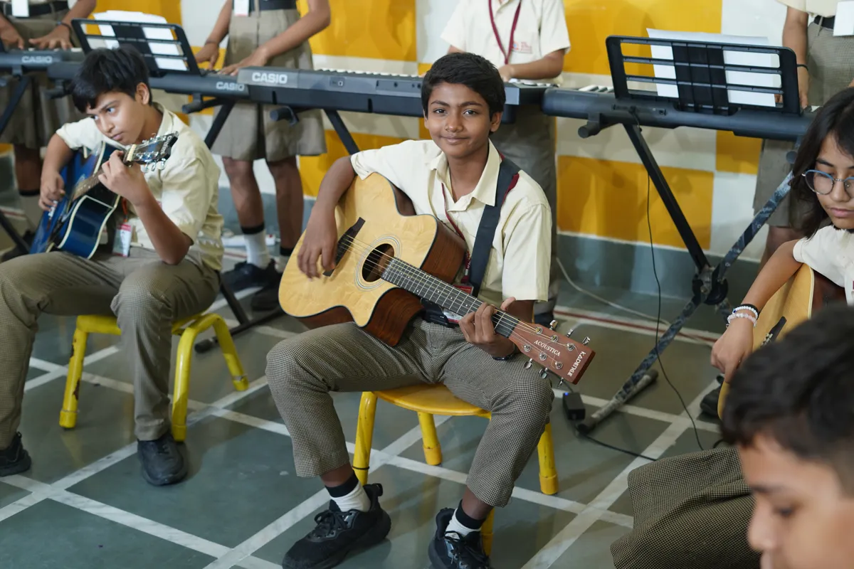 Students playing acoustic guitars in the music room, SKS World School, Greater Noida West