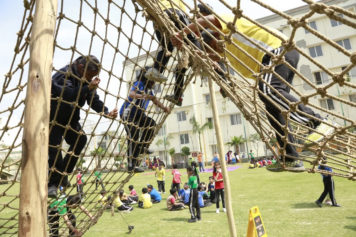 Students climbing a rope net during adventure activities at SKS World School, Greater Noida West