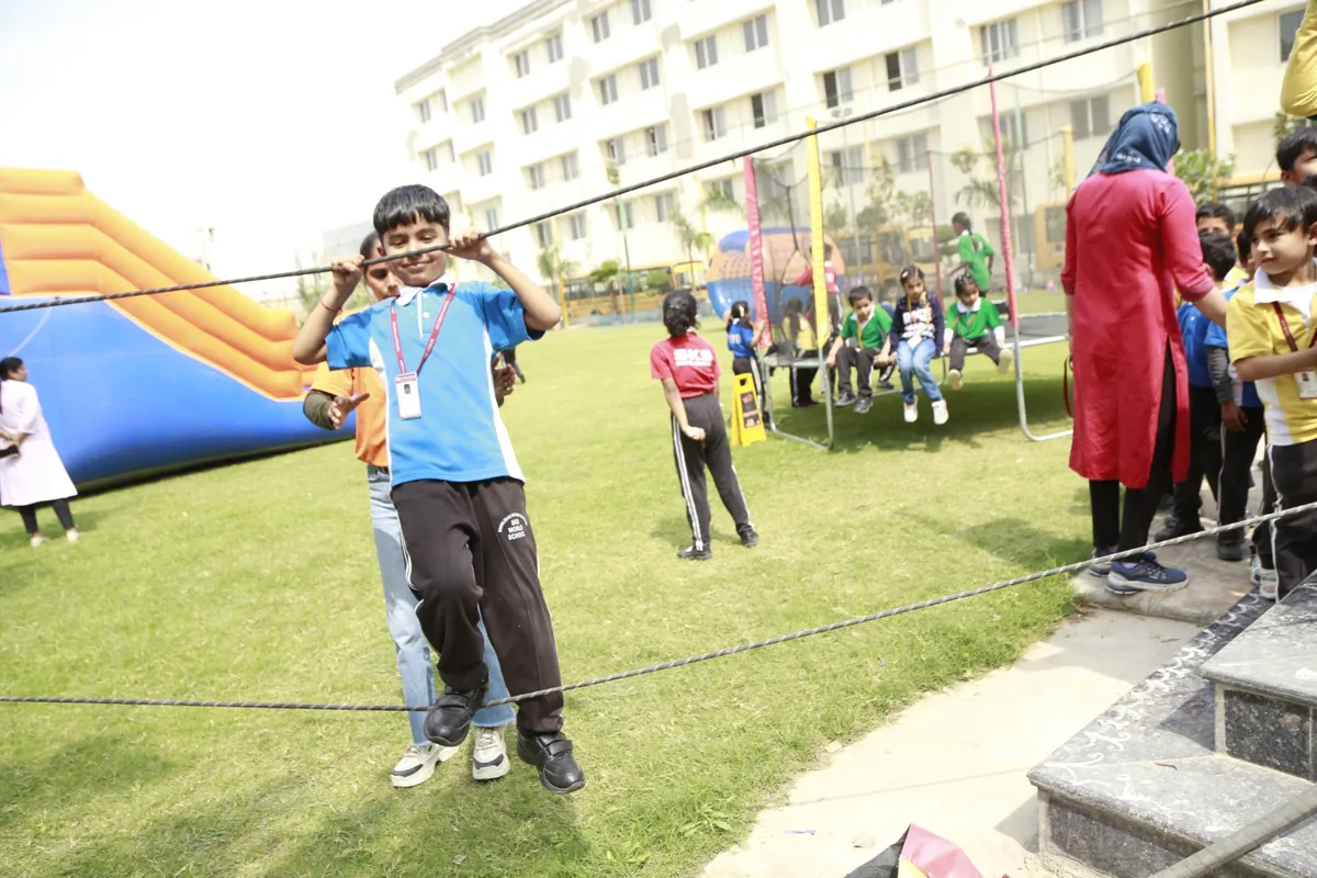 Student balancing on a rope walk on the school lawn at SKS World School, Greater Noida West
