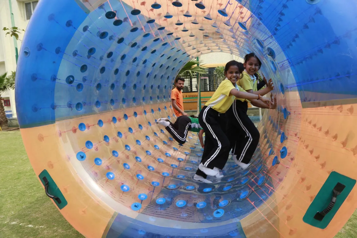 Student crawling through an inflatable zorb tunnel at SKS World School, Greater Noida West